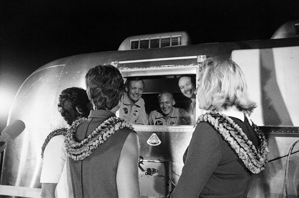 Apollo 11 astronauts looking at their wives through quarantine.