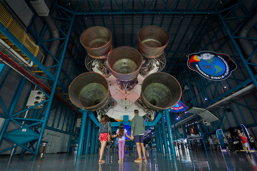 Family stares up in awe at Saturn V Rocket on display at Kennedy Space Center Visitor Complex.