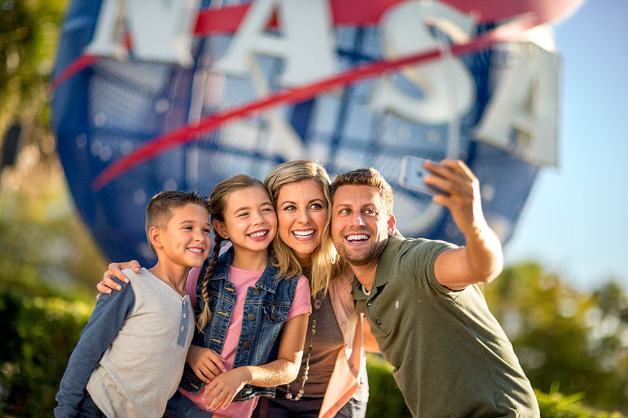 Family taking a selfie at the park entrance next to the NASA meatball